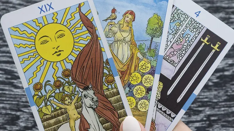 A hand holding three tarot cards